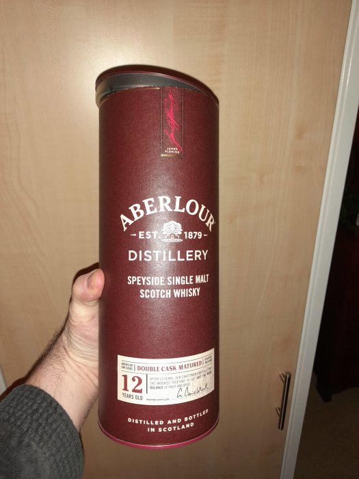 Hand håller Aberlour Distillery whiskycylinder, 12 år, Double Cask Matured, Speyside single malt.