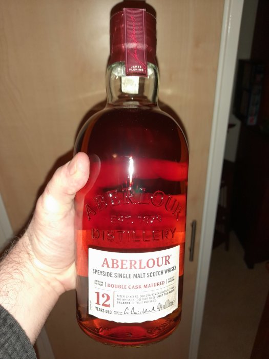 Flaska Aberlour 12 år gammal single malt scotch whisky hålls i hand.