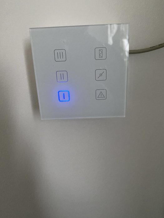 Modern vit väggströmbrytare med upplysta knappar och symboler. En knapp lyser blått.