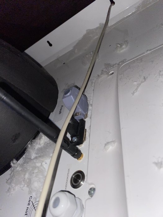 Inuti en apparat, närbild på elektriska komponenter, kablar och montering, damm och skräp synliga.