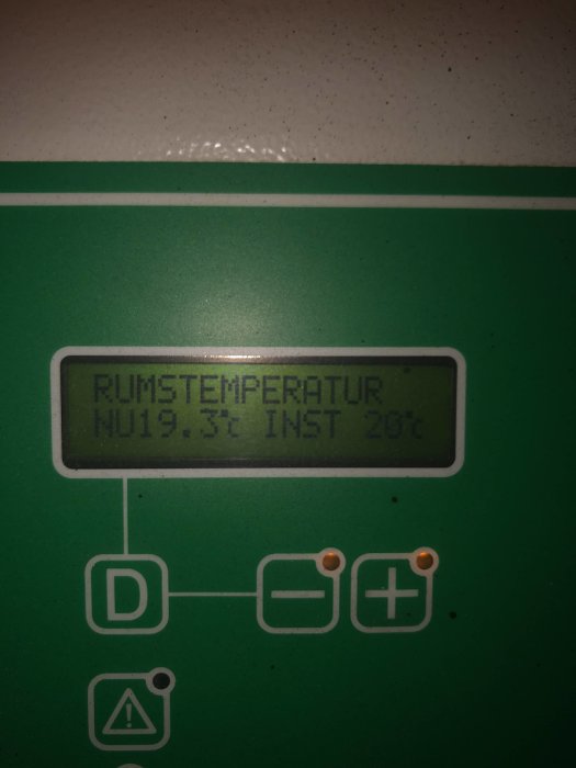 Digital display på en termostat visar rumstemperatur 19,3°C, inställd temperatur 20°C, på en grön bakgrund.