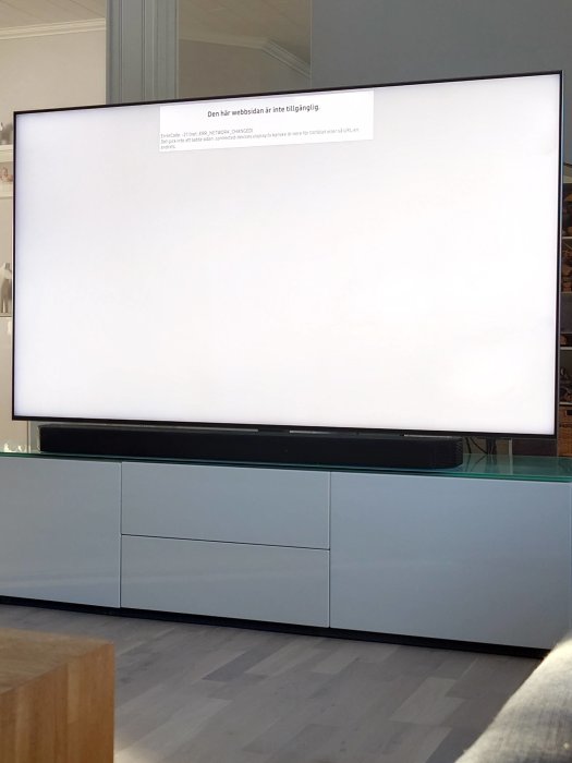 Stort TV-skärm med felmeddelande, ljust rum, modern möblering, skandinavisk stil.