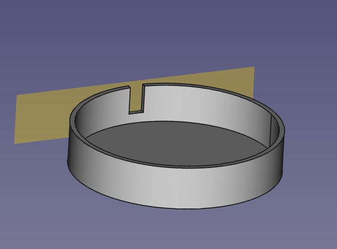 3D-modell av en enkel grå ring eller bricka med en skåra, blå bakgrund, beige form i hörnet.