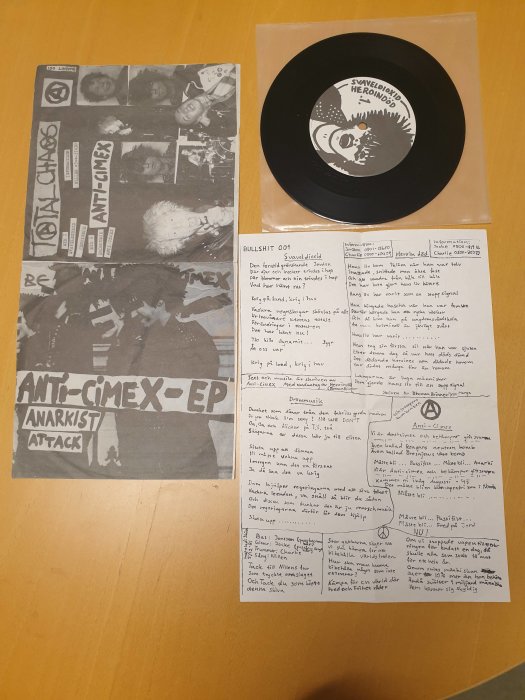 Vinylskiva, omslag och textblad med punkestetik, anarkistiskt tema, handskrivna anteckningar, svartvitt fotokollage.