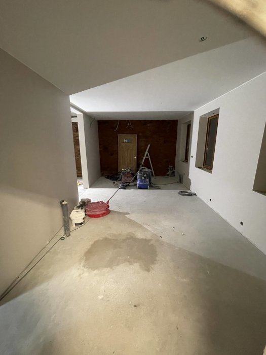 Omfattande renovering pågår inuti hus, oavslutade väggar och golv, byggmaterial och verktyg utspridda.