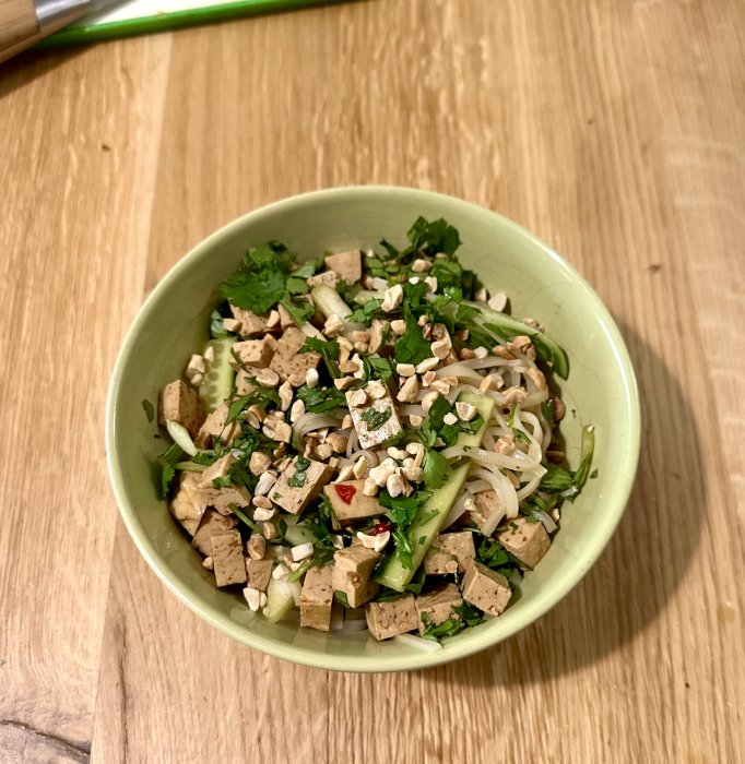 En skål med tofu, nudlar, koriander och hackade jordnötter; en fräsch vegetarisk asiatisk maträtt.