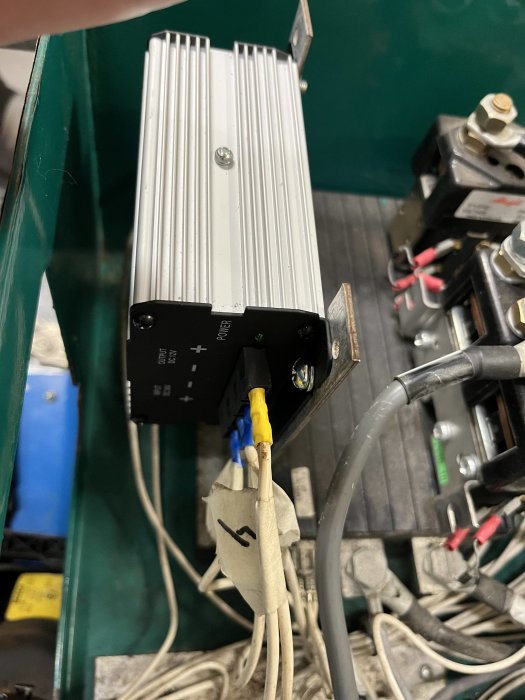 Elektronisk apparat med kylflänsar, kablar, och anslutningar i industriell miljö.