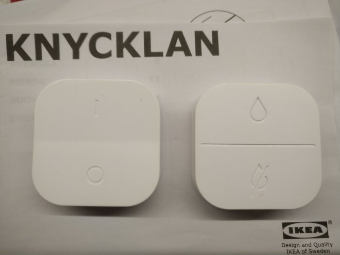 IKEA KNYCKLAN vattentät fjärrkontroller på manual, minimalistisk design, vita, symboler för ström och dropp.