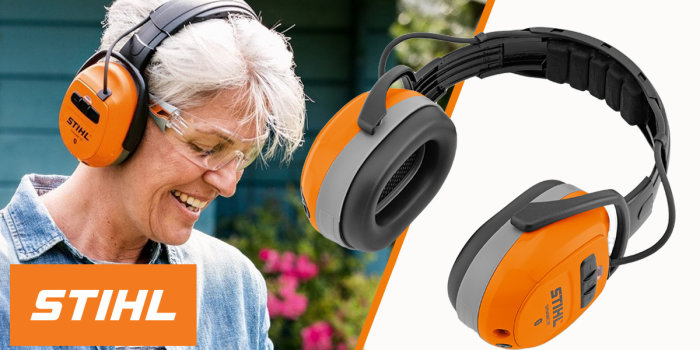 Kvinna ler, bär hörselskydd. Hörselkåpor med STIHL-logotyp, svart och orange detaljer, säkerhets- och skyddsutrustning.