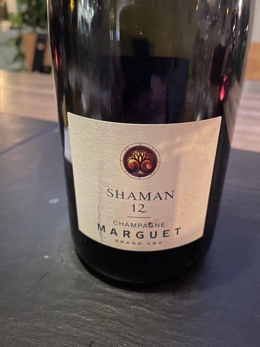 Flaska champagne "Shaman 12" av Marguet, Grand Cru, på ett mörkt underlag.