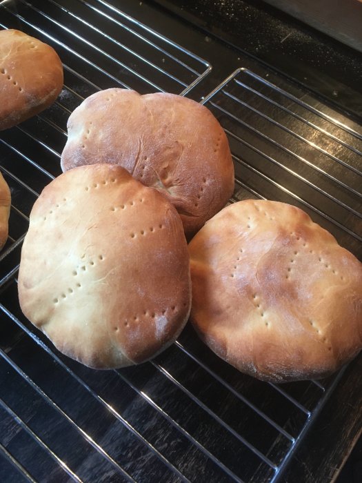 Nybakade runda bröd på kylgaller, gyllenbruna, fluffiga, hemgjorda, prickade med hål.