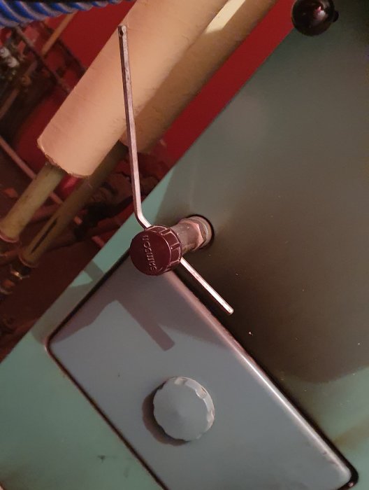 Nyckel i lås, turkos yta, skruv, oskarpt bakgrund, delar av träräcke, industriell känsla.