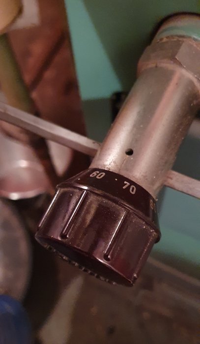 Termostatventil på en radiator, närbild, graderade inställningar synliga, inomhus, fokus på nummer 60 till 80.