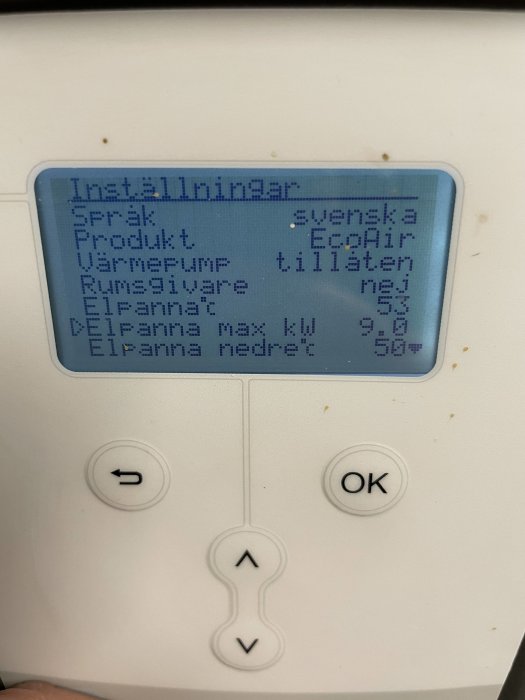 LCD-panel på en vit maskin, visar inställningar på svenska, knappar för navigering, blå bakgrundsbelysning.