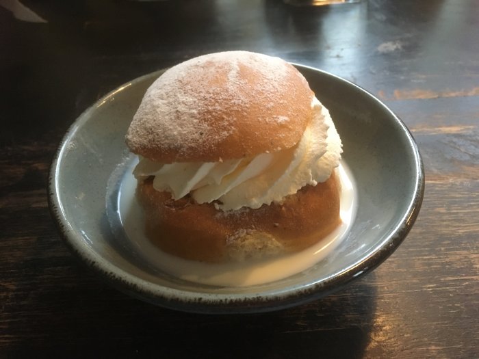 En semla med fluffig grädde på ett fat, pudrat med florsocker, traditionellt svenskt fikabröd.