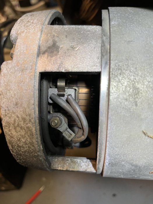 Bild på dammig maskindel, fokus på inre mekanism, slitage synligt, komplexa metallkomponenter, teknisk utrustning.