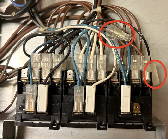 Elektrisk panel med säkringar och oorganiserade kablar, en lös kontakt synlig.