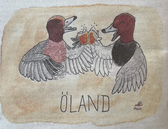 Två ankor skålar med öl, konsttryck på tyg, texten "ÖLAND" nedanför, färger i rött och brunt.