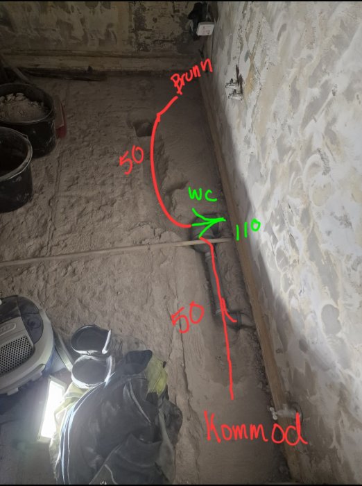 Renovering pågår, rör och mått angetts på golvet, avstånd markerade för installationer.