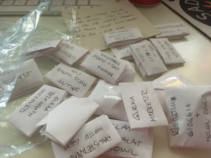 Hopvikta papperslappar med handskriven text framför ett tangentbord och plastpåse.