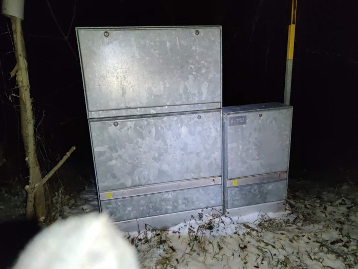 Metallskåp med nummer i mörker, snö på marken och delvis i bildens hörn.