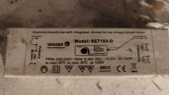 Elektronisk transformator, dimmer för halogenlampor, specifikationer, modell SET105-D, VADSBÖ, CE-märkt, smutsig bakgrund.