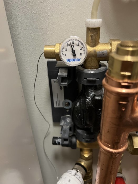 VVS-installation med temperaturmätare, mässingskopplingar och ventiler. Uponor märke synligt.
