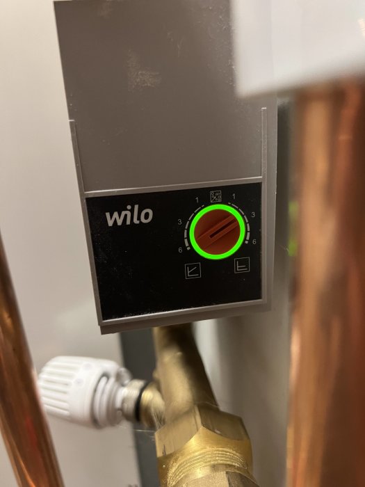 Cirkulationspump för värme med kontrollpanel och inställningar, kopplad till kopparledningar.