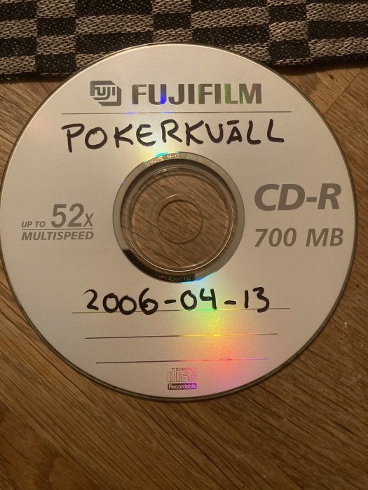 En Fujifilm CD-R med handskriven text "Pokerkväll" och datumet "2006-04-13", ligger på träyta.