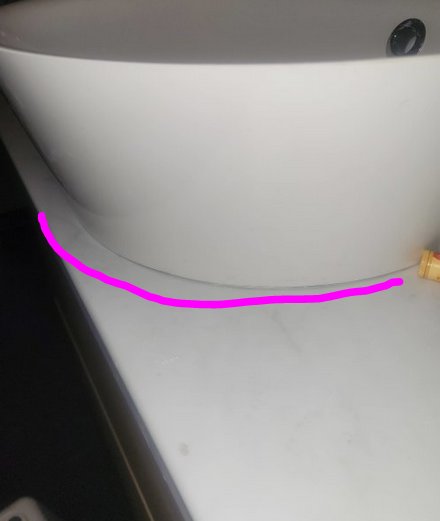 Vit tvättställ mot vit bakgrund med rosa markering längst ner på bilden.