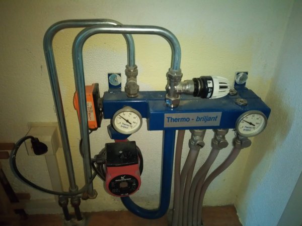 Värmesystemkomponent med rör, mätare, ventiler och en cirkulationspump, monterad på vägg, industriell känsla.