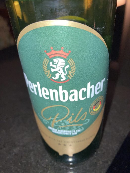 Etikett på Perlenbacher Pils-flaska med lejon och krona i sköld, bryggd enligt tysk renhetslag.
