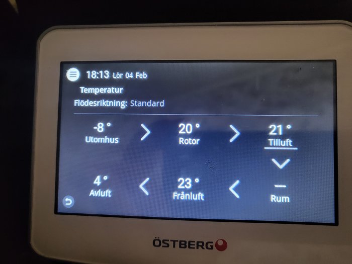 Digital termostat med temperaturvärden för inomhus och utomhus, flödesriktning, datum och tid.