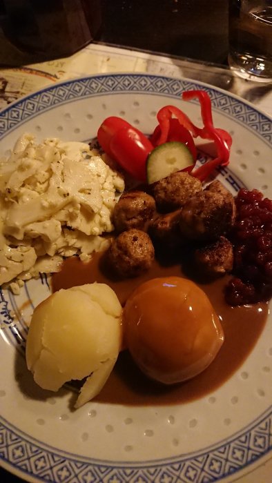 Svensk maträtt: köttbullar, potatis, brunsås, lingonsylt, kålrot, röd paprika och gurka.