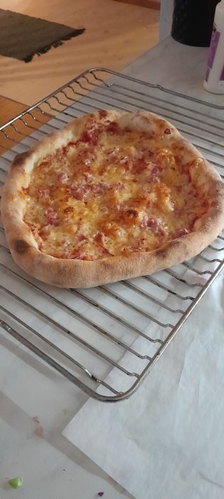 Nybakad pizza på kylställning, gyllene ost, uppblåst kant, träbord i bakgrunden.