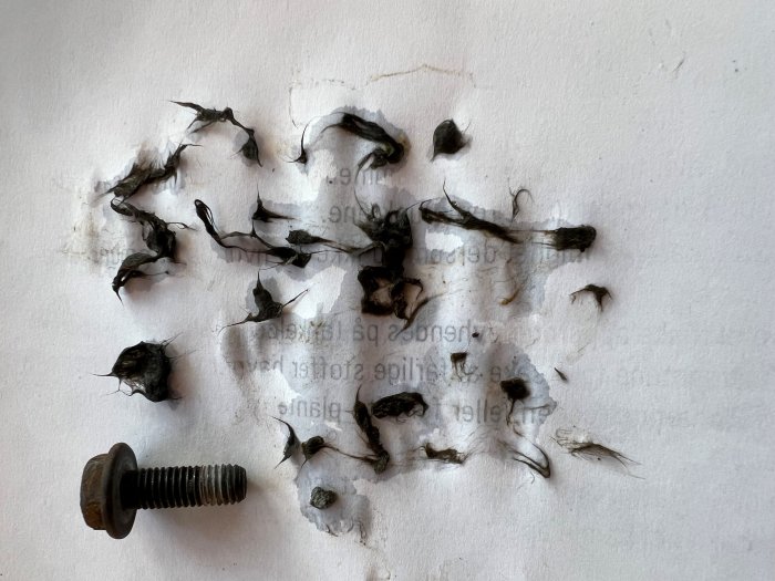 Förstört papper med text, rostig skruv, brända eller ruttna delar, texturbrott och skuggor.