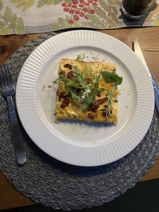 Frukosttallrik med omelett, ruccola, soltorkade tomater, gaffel, kaffe, färgglad löpare.