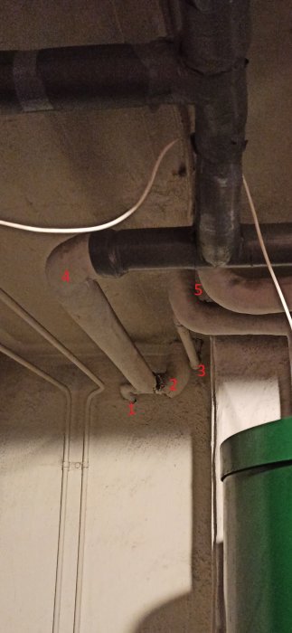 Rörledningar längs vägg och tak, numrerade punkter, skuggor, omarkerad kabel, synligt slitna ytor.