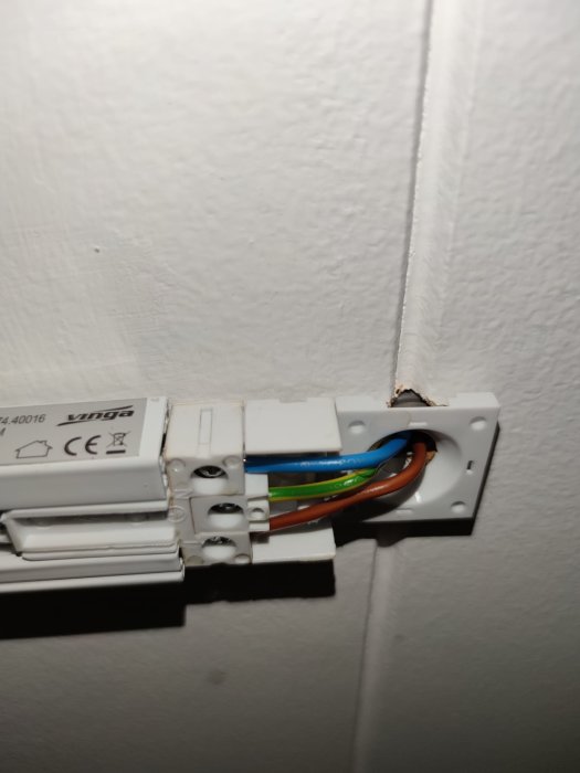Omonterad ljusbrytare, synliga elektriska kablar, vit vägg, installationsarbete, CE-märkt komponent.