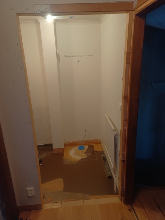 Ett rum under renovering med exponerad golvyta, väggar delvis förberedda, upplyst av överljus.