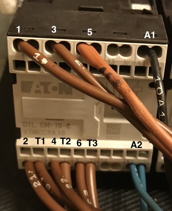 En kontaktor med märkta elektriska anslutningar och koppartrådar.