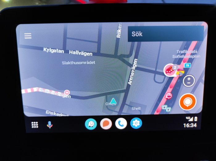 GPS-navigator i bil visar karta, trafikinformation och ikoner för tjänster.