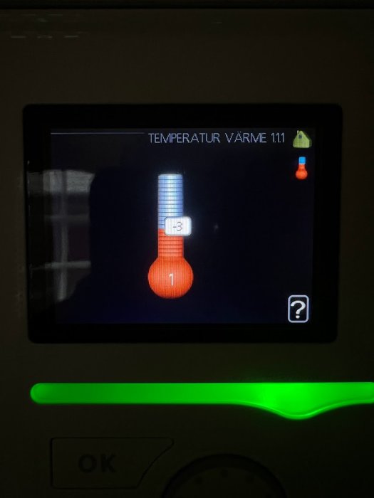 Digital display visar temperaturinställning, termometerikon, varm zon 1.11, grön lampa, OK-knapp, informationssymbol, mörk bakgrund.