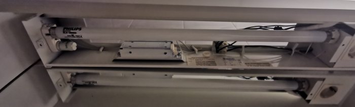 Intern mekanism av lysrörsarmatur, inklusive lysrör, ballast och kablage.