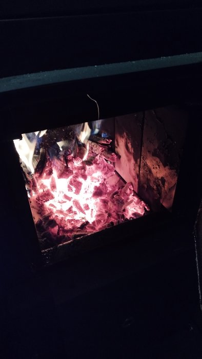 Brinnande ved i en öppen spis, med glödande kol och lågor. Värme, komfort, hemtrevnad.