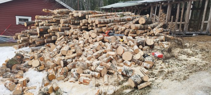 En hög med nyligen kapade vedträn, motorsåg, vinter, vid en vedbod.