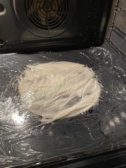 Bränd, smält plastfolie i en ugn; troligen ett misstag under matlagning eller rengöring.