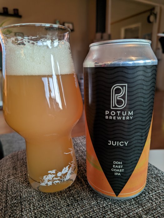 Ett glas med öl, skumtäcke, bredvid en burk märkt "Potum Brewery, JUICY, DDH East Coast IPA".