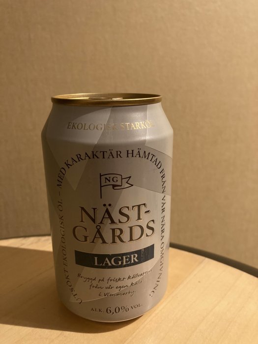 En ölburk märkt "NÄSTGÅRDS Lager", ekologisk, 6% volym, på träyta.