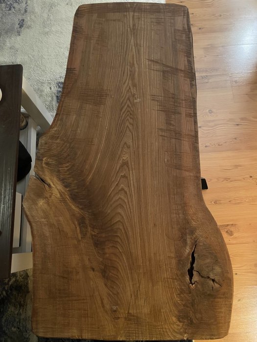 Träbord med organiska former på ett trägolv nära textil. Naturlig, rustik stil.